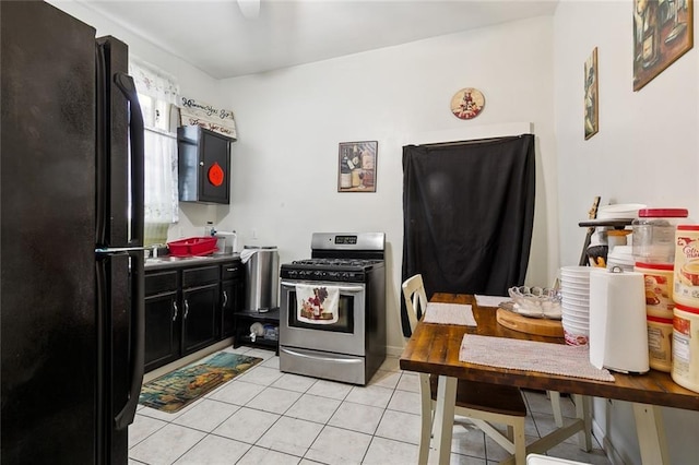 kitchen featuring stainless steel range with gas cooktop, black refrigerator, and light tile patterned floors