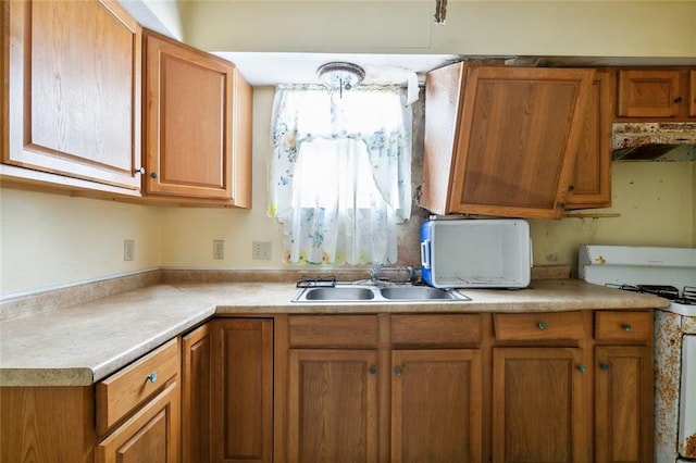 kitchen featuring white range oven, sink, and range hood