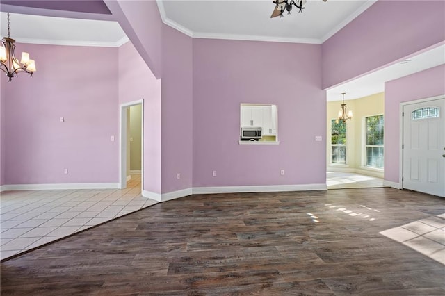 interior space with crown molding, hardwood / wood-style floors, a high ceiling, and ceiling fan with notable chandelier