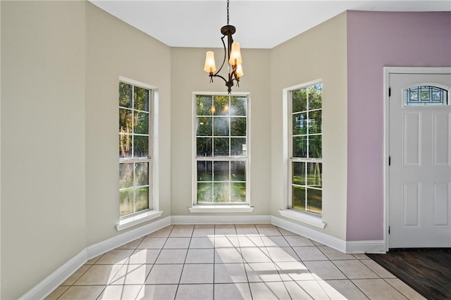 unfurnished dining area featuring light tile patterned floors, a wealth of natural light, and an inviting chandelier