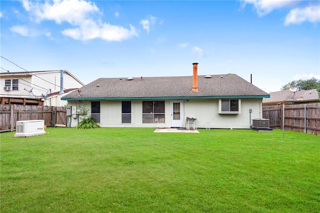 back of property with central AC unit and a yard