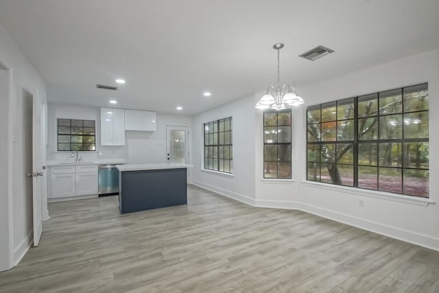 kitchen with dishwasher, a center island, light wood-type flooring, decorative light fixtures, and white cabinetry