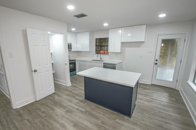 kitchen with a center island, sink, hardwood / wood-style flooring, white cabinetry, and stainless steel appliances