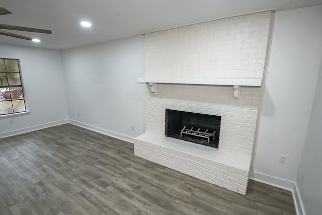 unfurnished living room featuring dark hardwood / wood-style flooring, a brick fireplace, and ceiling fan