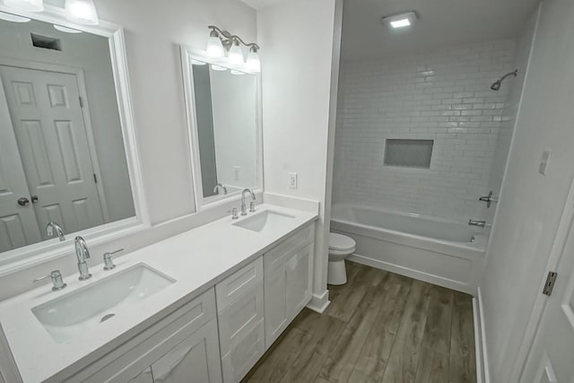 full bathroom with vanity, wood-type flooring, tiled shower / bath combo, and toilet