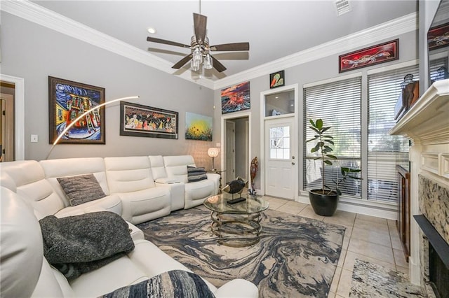 tiled living room with crown molding, a stone fireplace, and ceiling fan