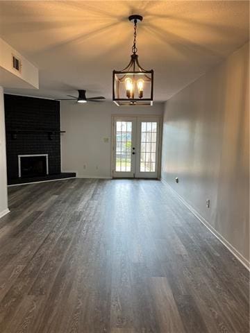 unfurnished living room featuring dark hardwood / wood-style flooring, a brick fireplace, french doors, and ceiling fan