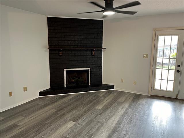 unfurnished living room featuring ceiling fan, wood-type flooring, and a fireplace