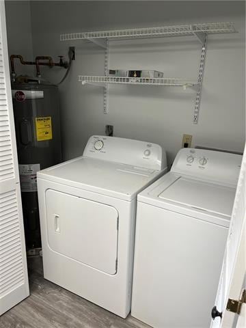 laundry room featuring wood-type flooring, electric water heater, and washer and dryer