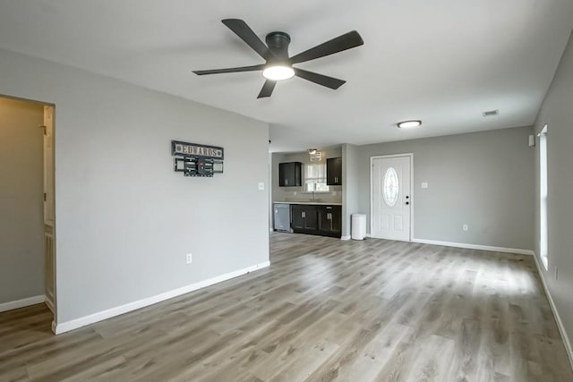 unfurnished living room with wood-type flooring, ceiling fan, and sink