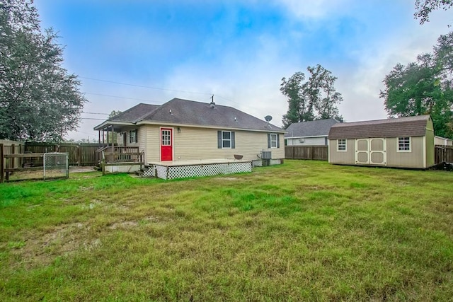 back of house with a yard, cooling unit, a storage shed, and a wooden deck