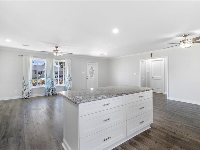 kitchen with light stone countertops, white cabinetry, ceiling fan, dark wood-type flooring, and a kitchen island