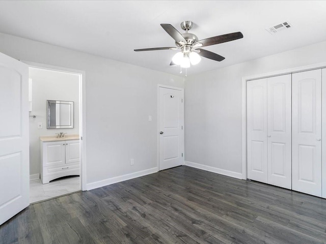 unfurnished bedroom with dark hardwood / wood-style floors, ceiling fan, a closet, and ensuite bath