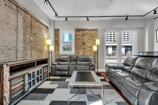 living room featuring rail lighting and brick wall