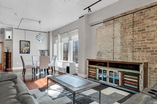 living room featuring hardwood / wood-style flooring, brick wall, and track lighting