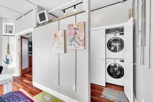 laundry room featuring wood-type flooring and stacked washer and dryer