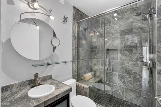 bathroom featuring vanity, toilet, and a shower with door