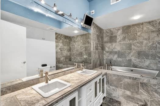 bathroom with vanity, tile walls, and tiled tub