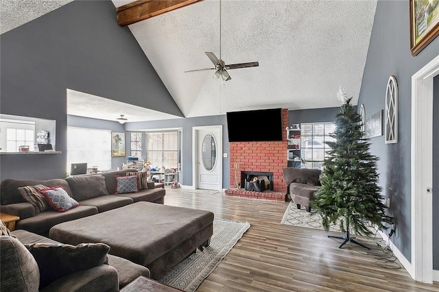 living room with hardwood / wood-style flooring, beam ceiling, a textured ceiling, and a brick fireplace