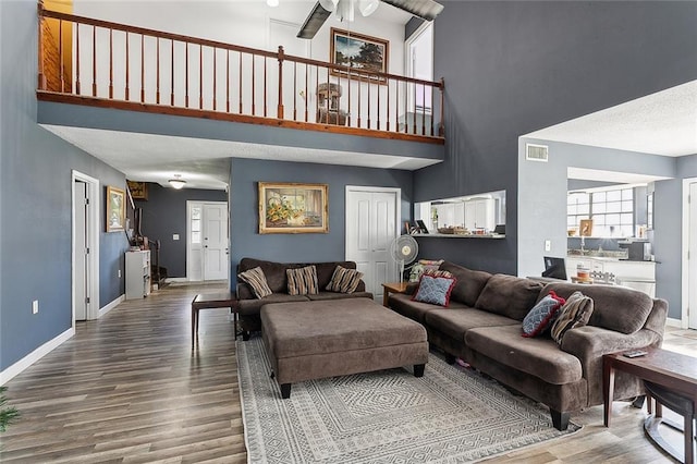 living room featuring hardwood / wood-style flooring, ceiling fan, and a high ceiling