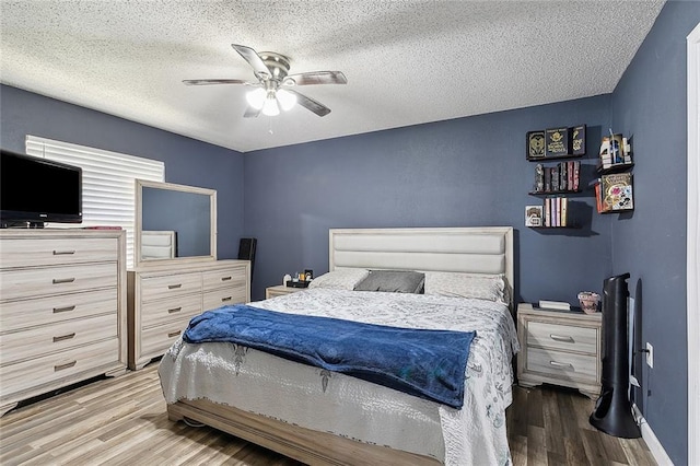 bedroom with ceiling fan, a textured ceiling, and hardwood / wood-style flooring