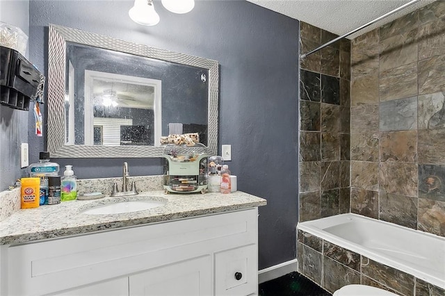 bathroom featuring a textured ceiling, vanity, and tiled shower / bath