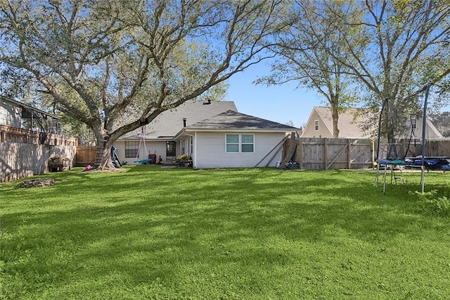 back of house with a trampoline and a lawn