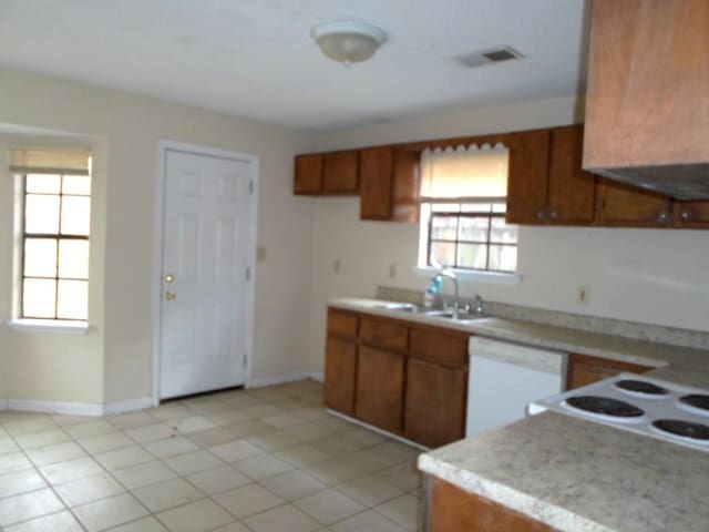 kitchen featuring a wealth of natural light, sink, white dishwasher, and light tile patterned floors