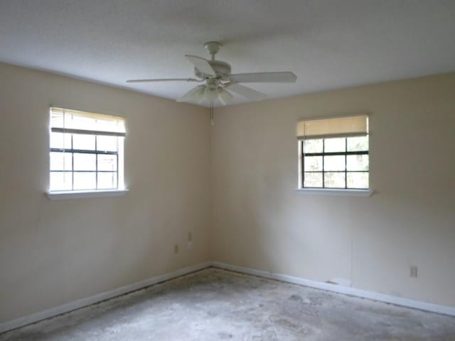 empty room featuring plenty of natural light, ceiling fan, and concrete flooring