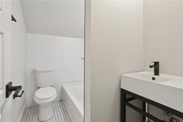 bathroom featuring toilet, tile walls, tile patterned floors, a bath, and sink