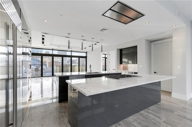 kitchen featuring light stone countertops, a kitchen breakfast bar, gas cooktop, sink, and a center island