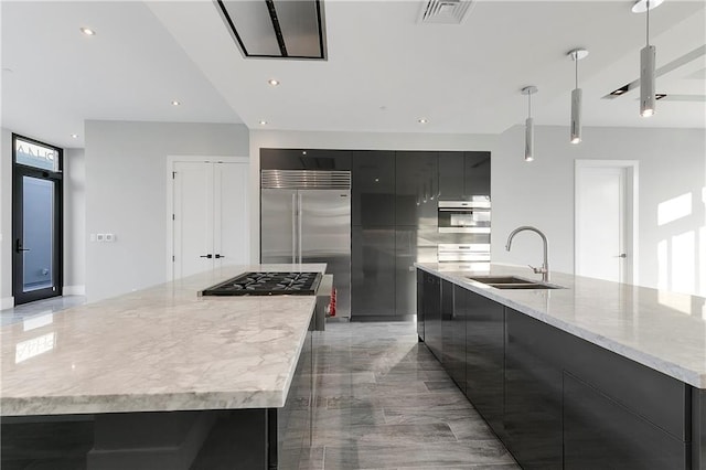 kitchen featuring a spacious island, sink, pendant lighting, oven, and built in fridge