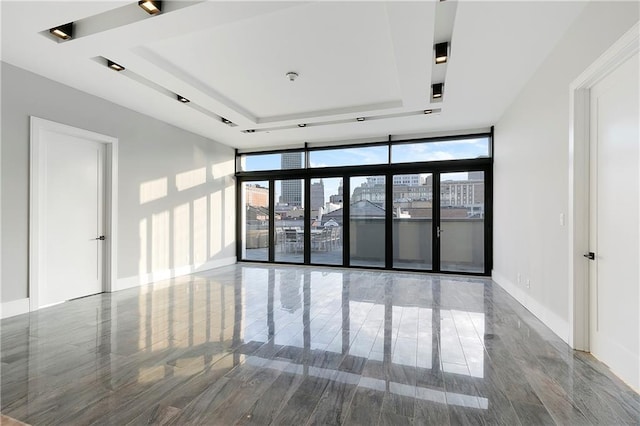 empty room with a raised ceiling and a wall of windows