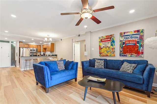 living room featuring crown molding, ceiling fan with notable chandelier, and light hardwood / wood-style floors