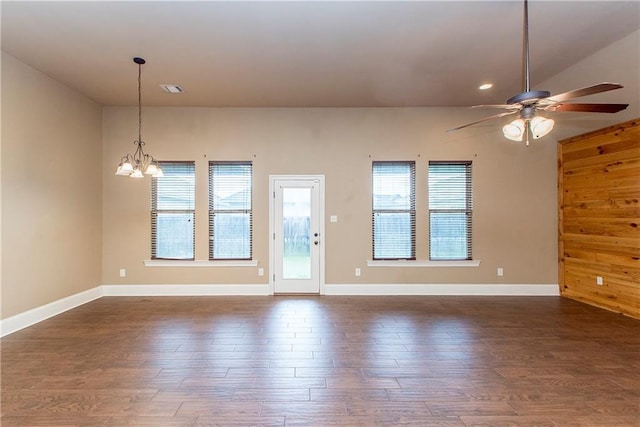 spare room featuring ceiling fan with notable chandelier, dark hardwood / wood-style flooring, and wooden walls