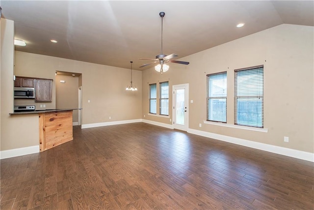 unfurnished living room featuring ceiling fan with notable chandelier, vaulted ceiling, and dark wood-type flooring