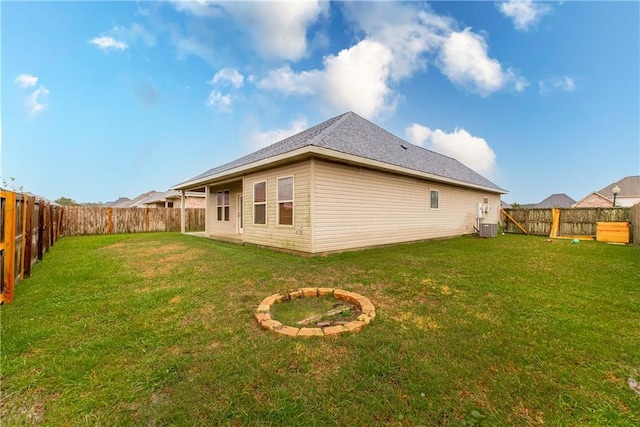 rear view of house featuring central AC unit and a lawn