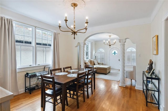 dining space featuring ornamental molding, light hardwood / wood-style floors, decorative columns, and a notable chandelier