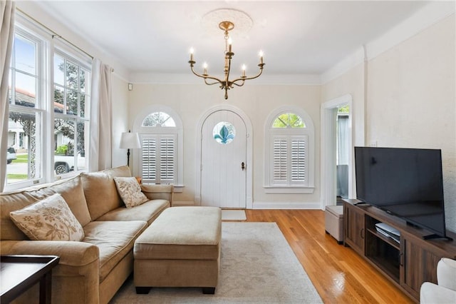 living room with light hardwood / wood-style flooring, ornamental molding, and an inviting chandelier