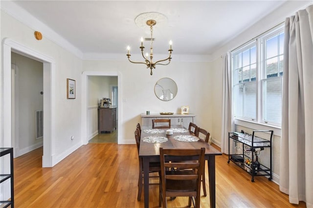 dining area with ornamental molding, a chandelier, and light wood-type flooring