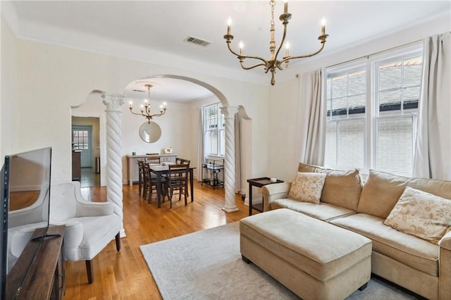 living room with ornate columns, crown molding, hardwood / wood-style floors, and a notable chandelier