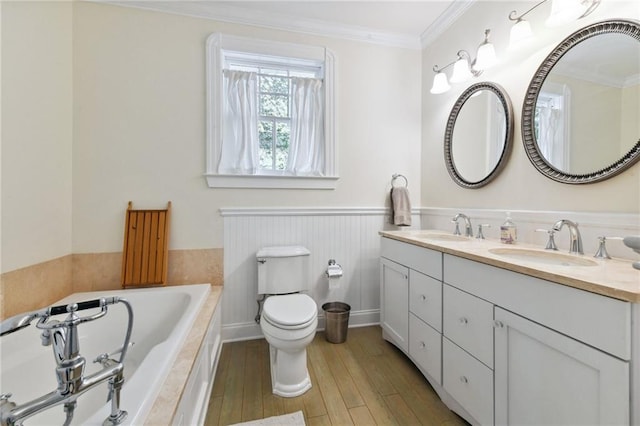 bathroom with tiled bath, crown molding, toilet, vanity, and hardwood / wood-style flooring