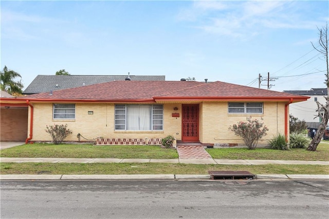 6301 S Rocheblave St, New Orleans, LA 70125 - view of front facade with brick siding, a front yard, a shingled roof, and driveway
