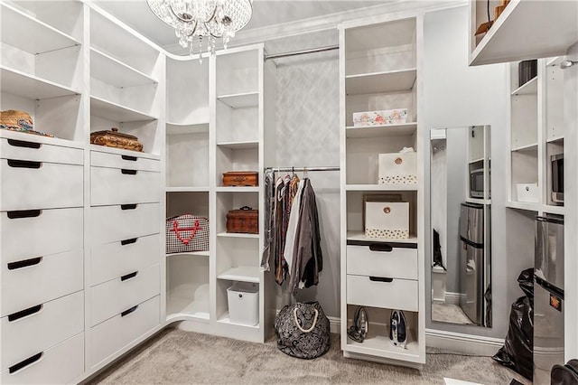 walk in closet with light carpet and an inviting chandelier