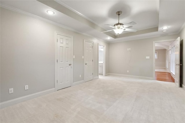 unfurnished bedroom featuring a tray ceiling, ceiling fan, crown molding, and light colored carpet