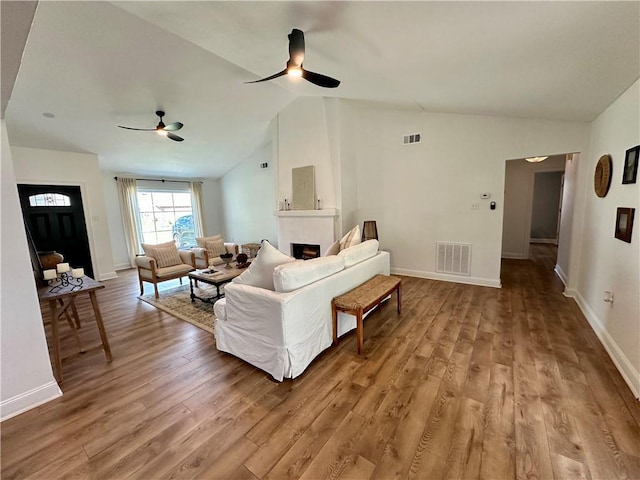 living room featuring hardwood / wood-style floors, a large fireplace, ceiling fan, and lofted ceiling