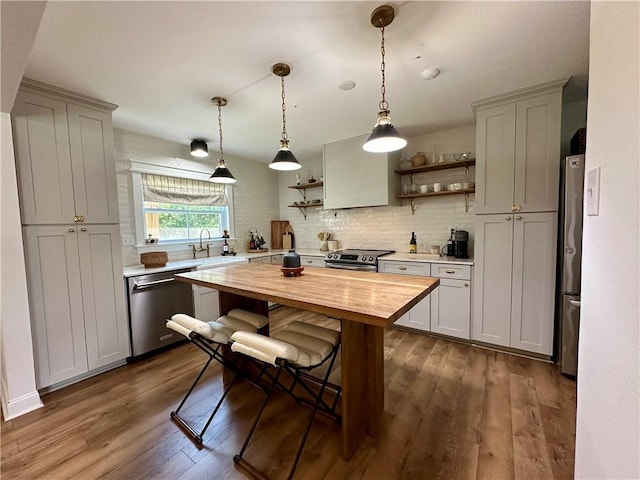 kitchen featuring dark wood-type flooring, wooden counters, sink, appliances with stainless steel finishes, and decorative light fixtures