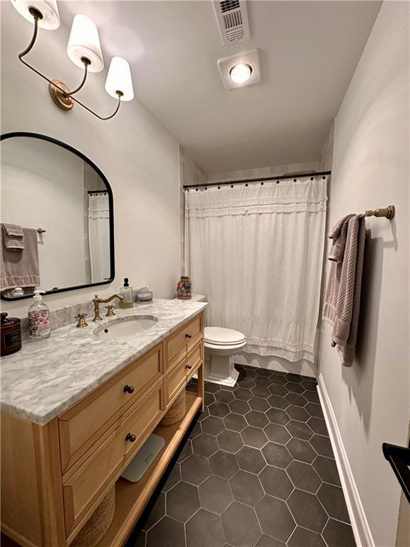 bathroom featuring tile patterned floors, vanity, toilet, and walk in shower