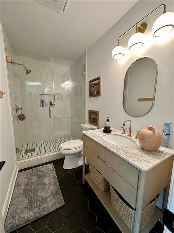 bathroom with tile patterned flooring, vanity, a shower with door, and toilet