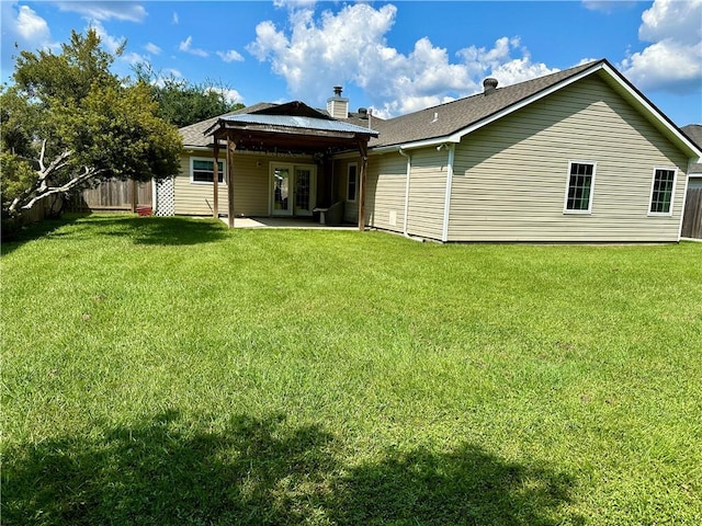 rear view of house with french doors, a patio area, and a lawn